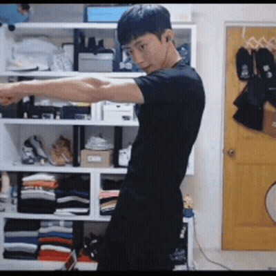 Young Man In Black Shirt By Closet Full Of Clothes GIF