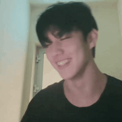 Young Man In Black Shirt Making Funny Face In Front Of Door GIF
