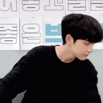 Young Man In Black Shirt Sitting By Wall With Signs GIF