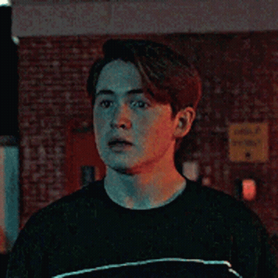 Young Man In Black T-Shirt In Front Of Brick Wall GIF