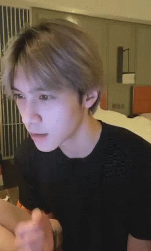 Young Man In Black T-Shirt Sitting On Bed GIF