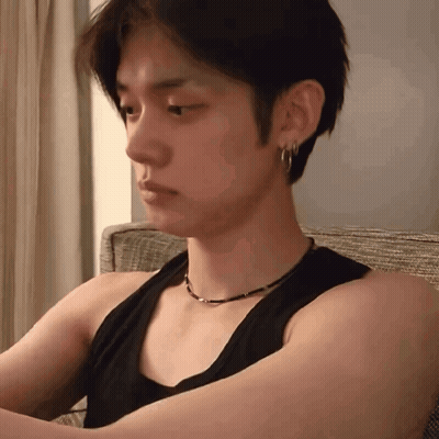 Young Man In Black Tank Top And Earrings Sitting On Couch GIF
