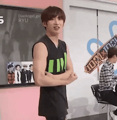 Young Man In Black Tank Top Arms Crossed In Front Of Pink Wall GIF