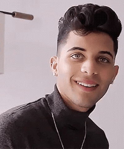 Young Man In Black Turtleneck And Necklace Smiling GIF