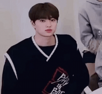 Young Man In Black Vest And Sweater Sitting GIF