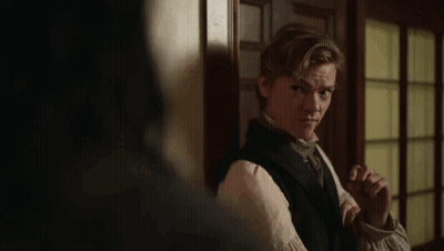 Young Man In Black Vest And Tie By Door In Dark Room GIF