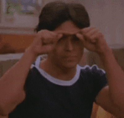 Young Man In Blue Shirt Making Funny Face On Couch GIF