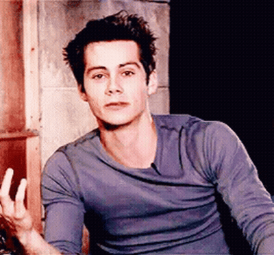 Young Man In Blue Shirt Sitting In Front Of Brick Wall GIF