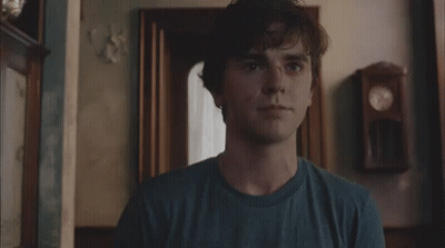 Young Man In Blue Shirt Standing In Front Of Clock GIF