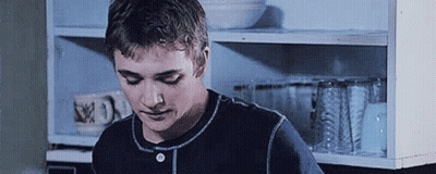 Young Man In Blue Shirt Standing In Front Of Shelf GIF