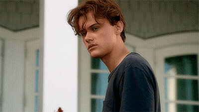 Young Man In Blue Shirt Standing In Front Of Window GIF