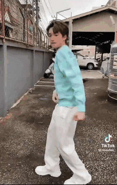 Young Man In Blue Sweater And White Pants On Sidewalk GIF