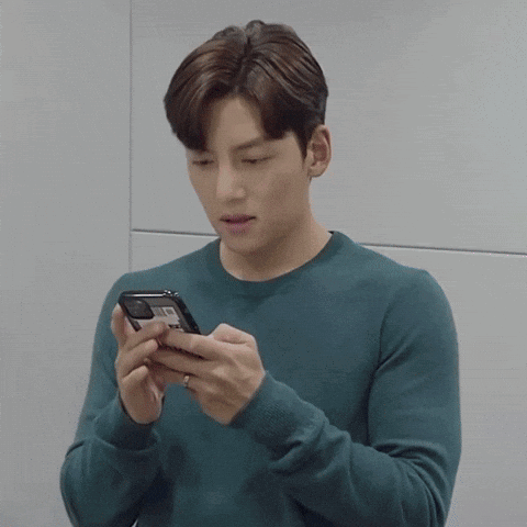 Young Man In Blue Sweater Looking At Cell Phone GIF
