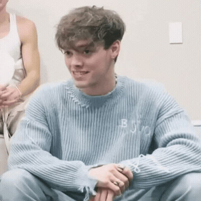 Young Man In Blue Sweater Smiling With Folded Hands GIF