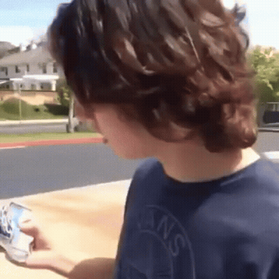 Young Man In Blue Vans Shirt Looking At Phone GIF