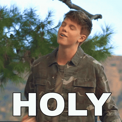 Young Man In Camouflage Jacket Standing Before Holy Sign GIF