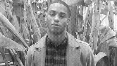 Young Man In Coat And Plaid Shirt By Tree GIF