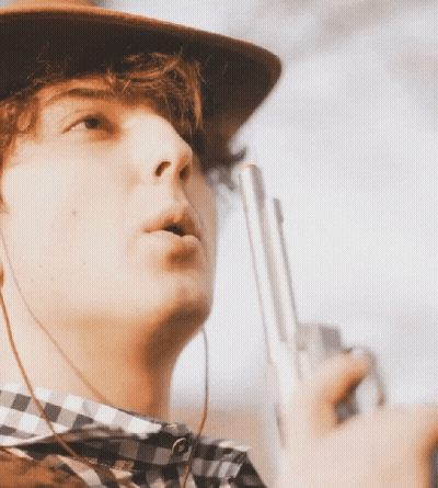 Young Man In Cowboy Hat And Plaid Shirt Holding Gun GIF