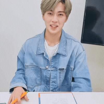 Young Man In Denim Jacket Sitting At Table GIF