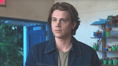 Young Man In Denim Jacket With Red Exit Sign GIF