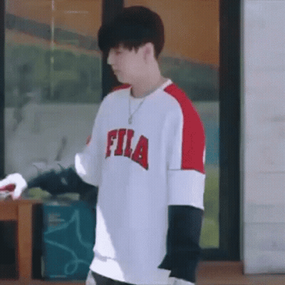 Young Man In Fila Shirt Standing In Front Of Window GIF