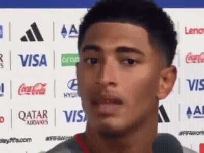 Young Man In Front Of Visa Coca Cola Qatar Airways Logos GIF