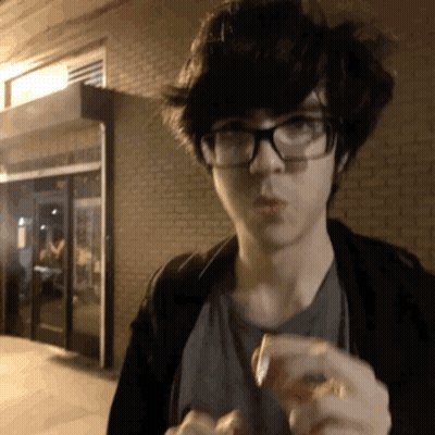 Young Man In Glasses And Black Jacket Eating GIF