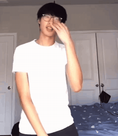 Young Man In Glasses And White Shirt By Bed GIF