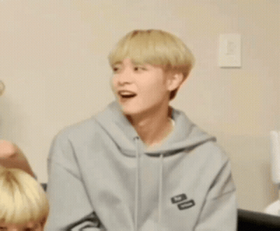 Young Man In Gray Hoodie Sitting On Couch GIF