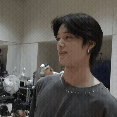 Young Man In Gray Shirt And Earrings By Mirror GIF