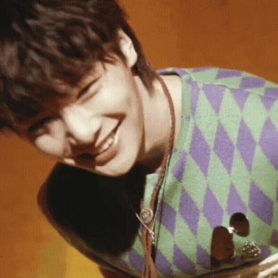 Young Man In Green And Purple Sweater Smiles GIF