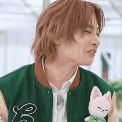 Young Man In Green Jacket Holding Stuffed Animal GIF