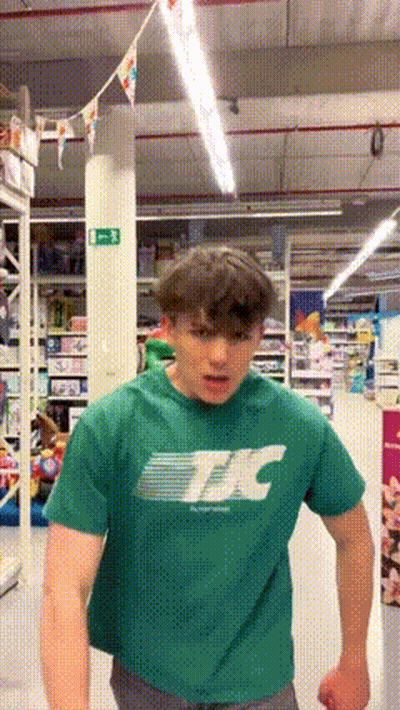 Young Man In Green T-Shirt Standing In Store GIF
