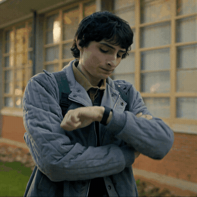 Young Man In Grey Jacket Looking At Watch GIF