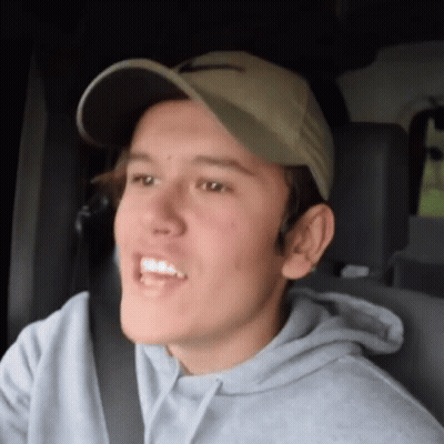 Young Man In Hat And Grey Hoodie Sitting In Car GIF