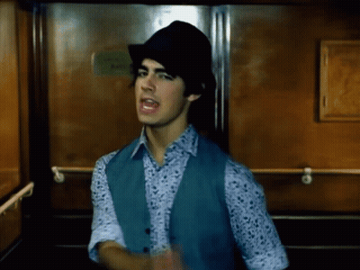 Young Man In Hat And Vest Standing In Elevator GIF