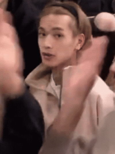 Young Man In Headband Sitting In Crowd GIF