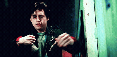 Young Man In Leather Jacket And Red Sweater Standing In Front Of Door GIF