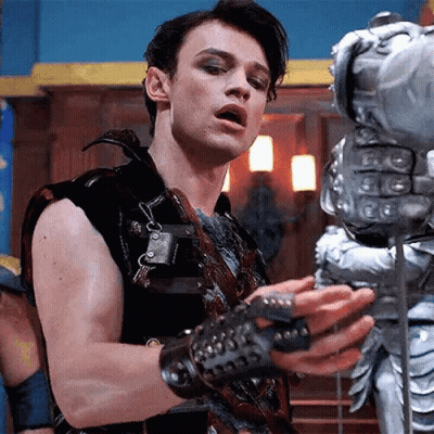 Young Man In Leather Vest Beside Knight Statue GIF