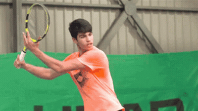 Young Man In Orange Shirt Swinging Tennis Racquet GIF