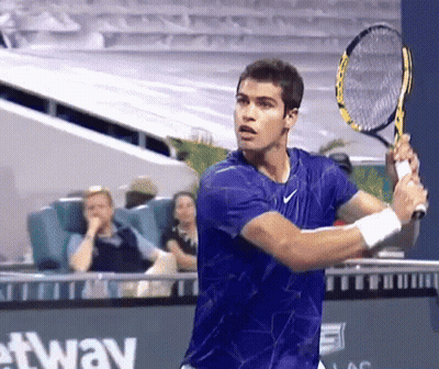 Young Man In Orange Shirt Swinging Tennis Racquet GIF