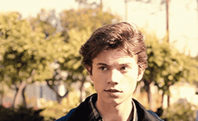 Young Man In Plaid Shirt And Blue Jacket Before Trees GIF