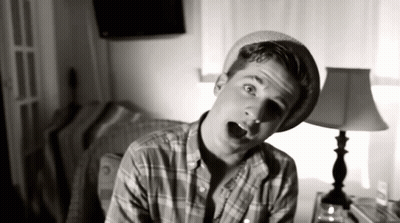 Young Man In Plaid Shirt And Hat In Front Of Lamp GIF
