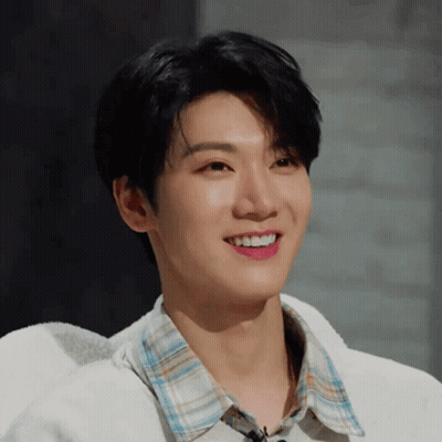 Young Man In Plaid Shirt And White Sweater Smiling GIF