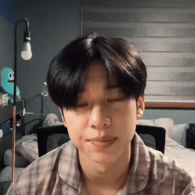 Young Man In Plaid Shirt Making Funny Face In Bedroom GIF