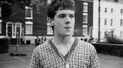Young Man In Plaid Shirt Standing In Front Of Building GIF