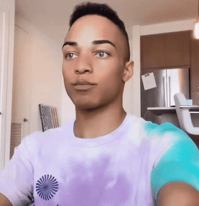 Young Man In Purple Tie Dye Shirt Looking At Camera GIF