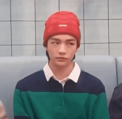 Young Man In Red Beanie And Green Blue Shirt Sitting On Couch GIF
