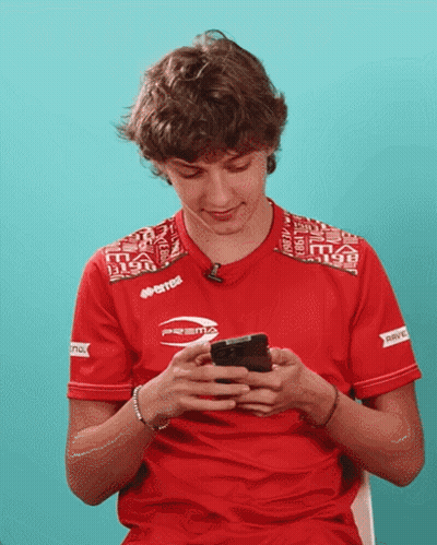 Young Man In Red Errea Shirt Looking At Phone GIF