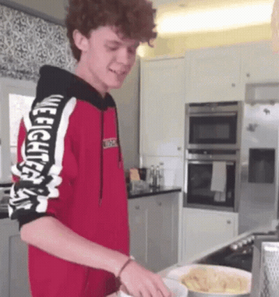 Young Man In Red Hoodie Cooking In Kitchen GIF